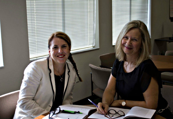 Two women sitting smiling at the viewer.