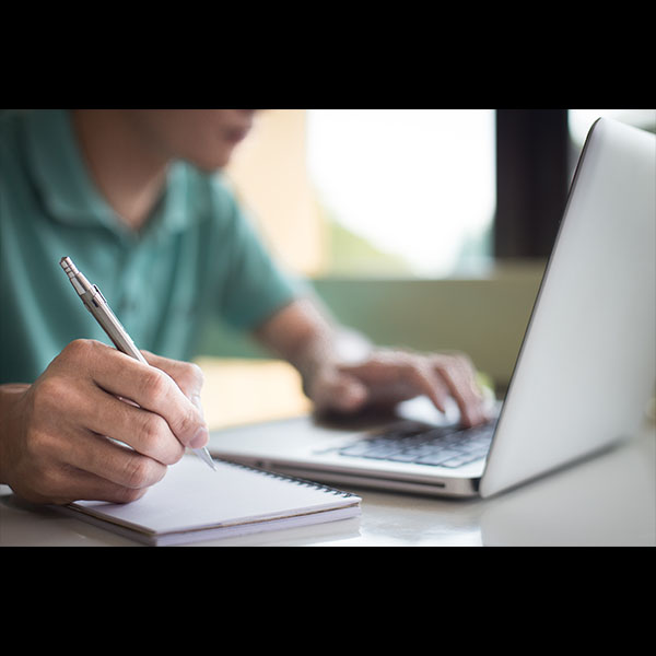 man taking notes in front of computer