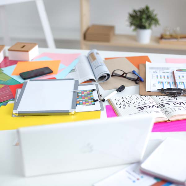 laptop, opened books and papers cluttering a desk