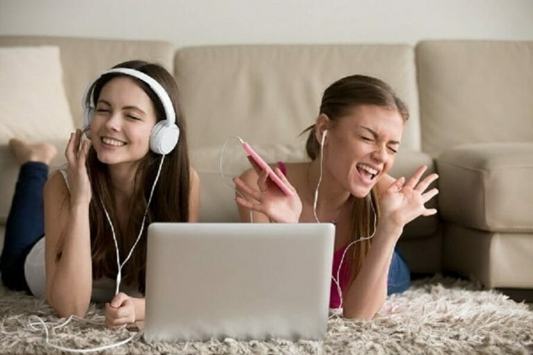 Two girlfriends in headphones having fun at home