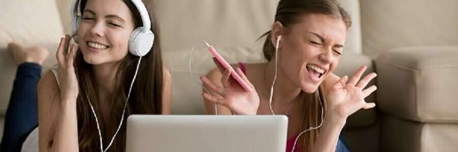 Two girlfriends in headphones having fun at home