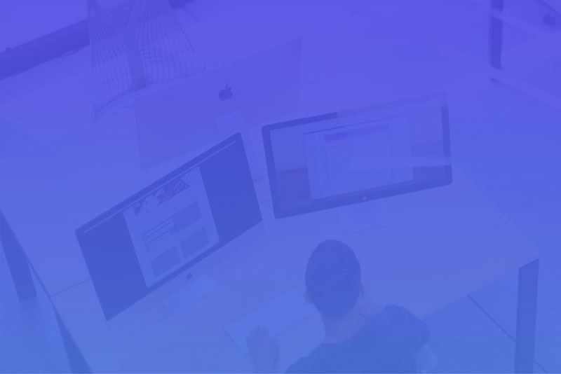 Young man sitting in front of two computers. Purple filyer