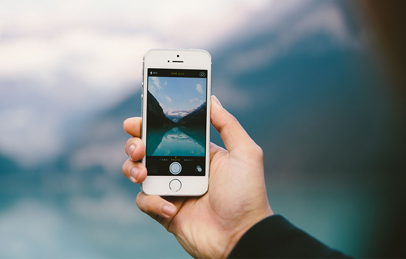 person using a smartphone to take a picture of a body of water