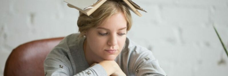 Portrait of student girl with open book on her head