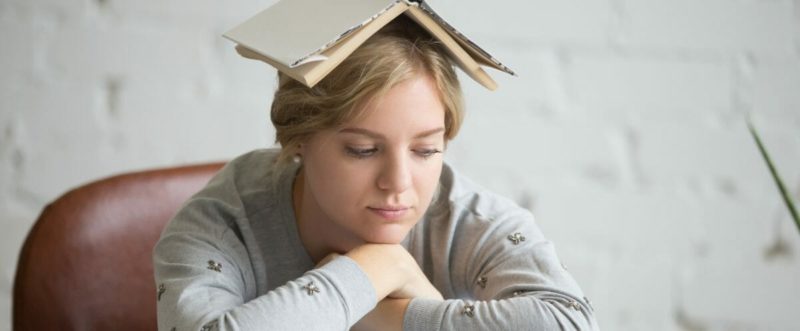 Portrait of student girl with open book on her head