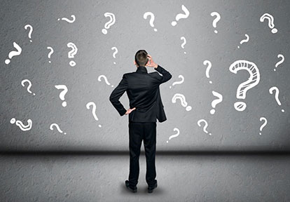 Businessman standing in front of floating question marks