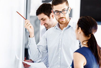 two young colleagues talking in front of a white board