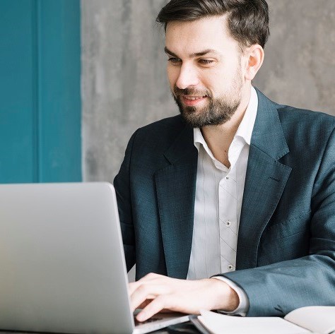 Young man tying on laptop computer