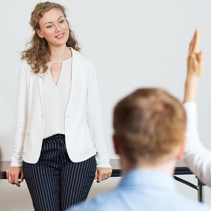 Female instructor at front of class taking questions from students