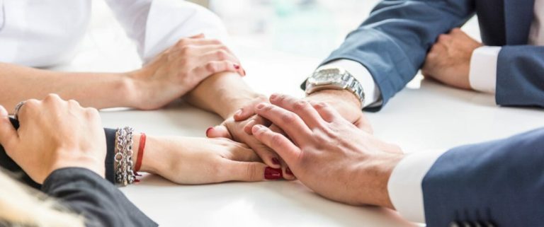 team member placing their hands over one another