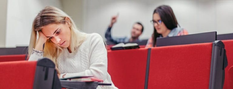 Young woman stating at her textbook with a frustrated expression