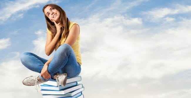 young pretty woman thinking and sitting on a big books pile Young pretty woman thinking and sitting on a big books pile
