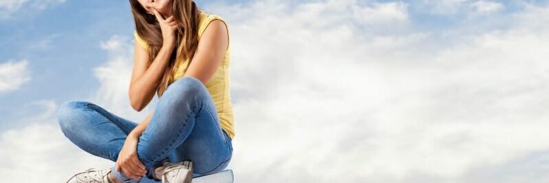 young pretty woman thinking and sitting on a big books pile Young pretty woman thinking and sitting on a big books pile