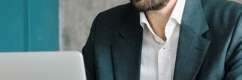 Man in business attire types on his laptop