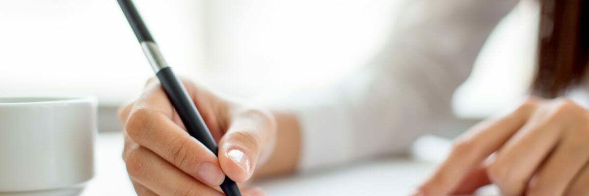 Hand of businesswoman writing on paper in office
