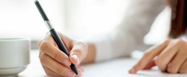Hand of businesswoman writing on paper in office
