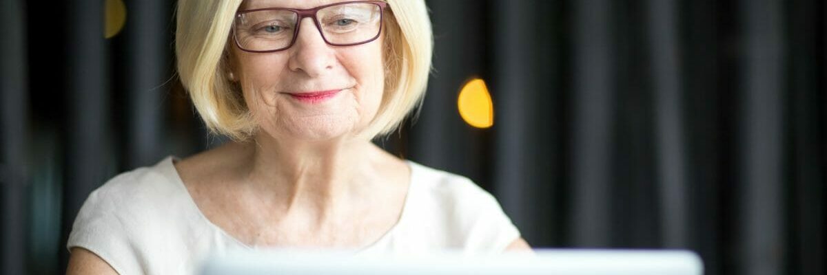 Portrait of positive senior woman using laptop