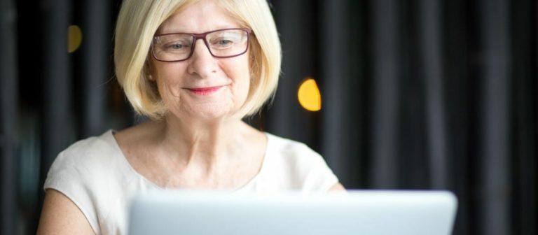 Portrait of positive senior woman using laptop