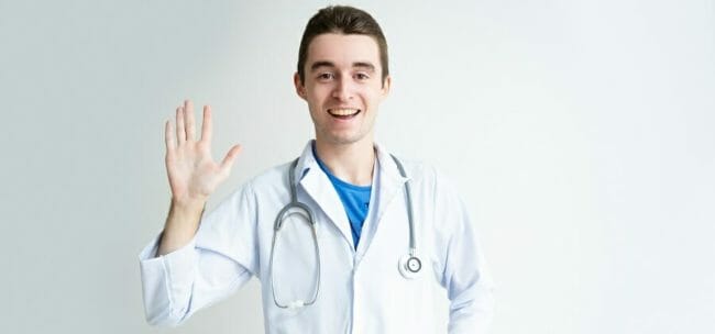 Friendly young male doctor waving hand Friendly young male doctor waving hand
