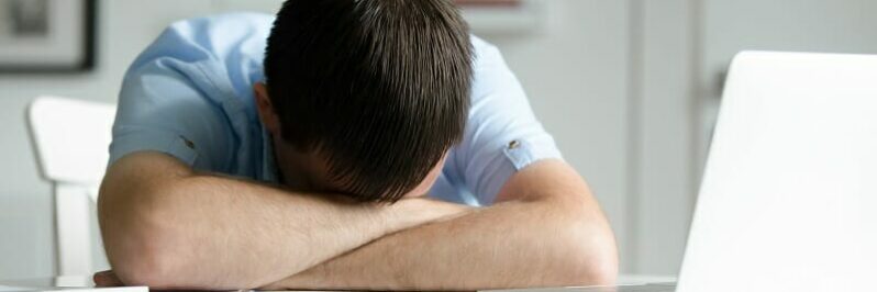 Portrait of a man lying down at desk near laptop