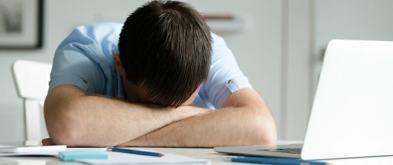 Portrait of a man lying down at desk near laptop