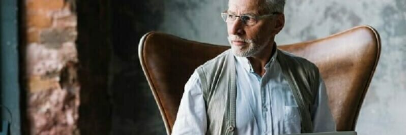Older male sitting in a chair staring off to the distance