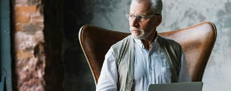 Older male sitting in a chair staring off to the distance
