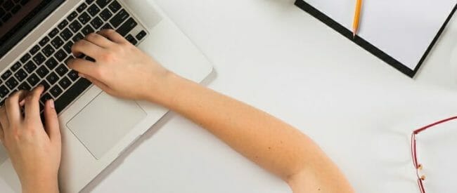 student working on laptop on a white desk