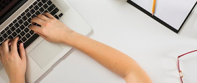 student working on laptop on a white desk