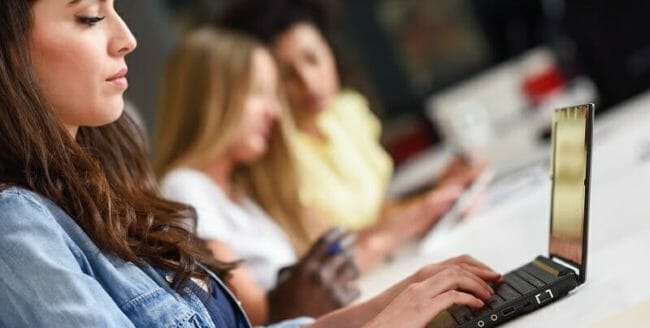 Young woman studying with laptop computer on white desk