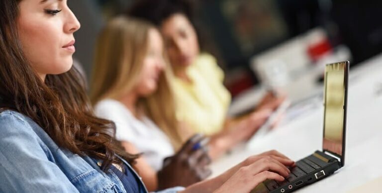 Young woman studying with laptop computer on white desk