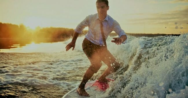 Water recreation Young man in wet clothes surfboarding at summer resort