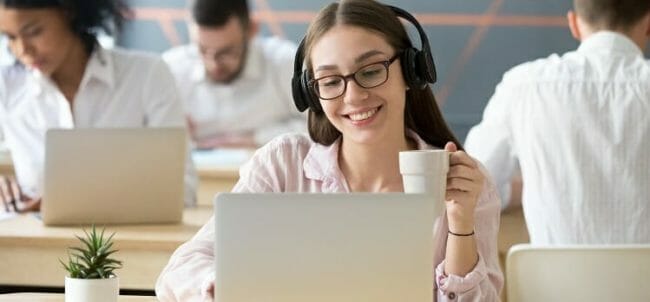 Smiling woman wearing headphones watching online video during co Smiling woman wearing headphones watching online video during co