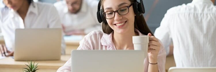 Smiling woman wearing headphones watching online video during co Smiling woman wearing headphones watching online video during co