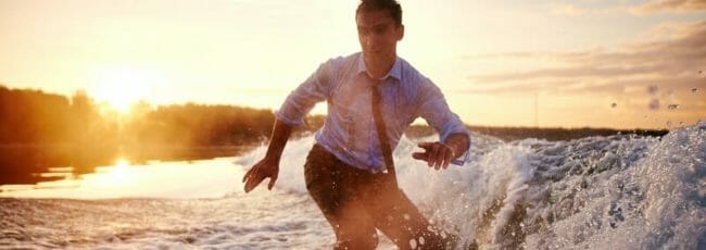 Young man in wet clothes surfboarding at summer resort