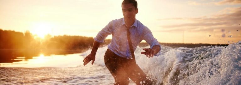 Young man in wet clothes surfboarding at summer resort