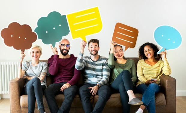colleagues sitting on a couch holding up though bubbles made from paper