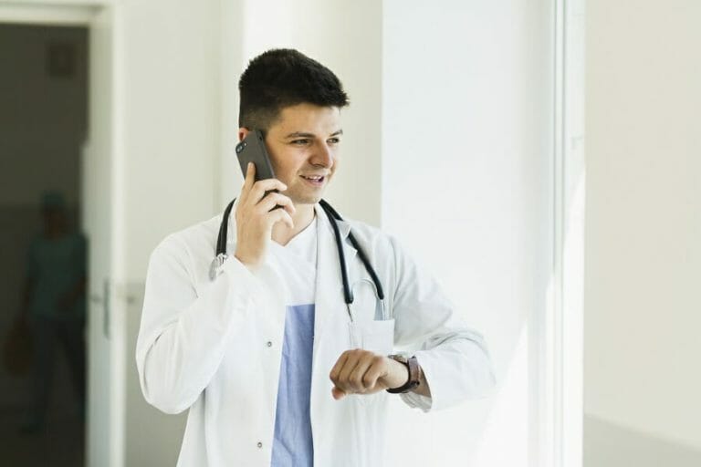male medical professional looking at their watch while on the phone