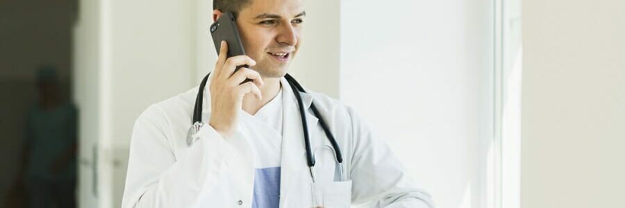 male medical professional looking at their watch while on the phone