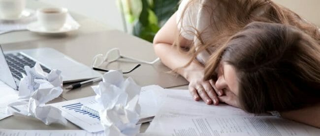 Woman sleeping on desk covered crumpled papers Woman sleeping on desk covered crumpled papers
