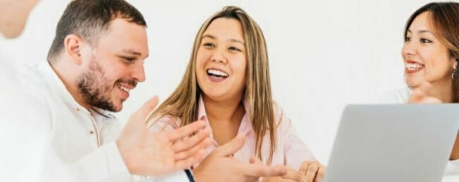 Group of smiling people in front of a computer
