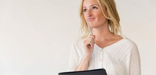 Pensive young woman holding pen and folder Pensive young woman holding pen and folder
