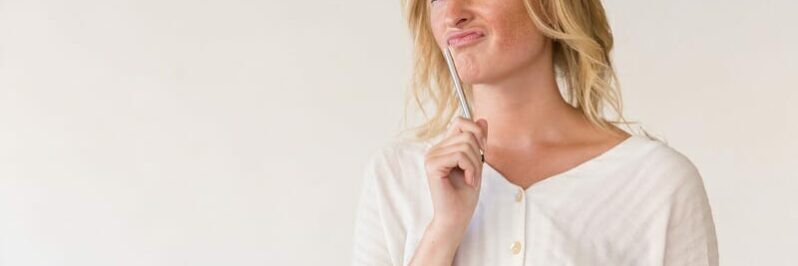 Pensive young woman holding pen and folder