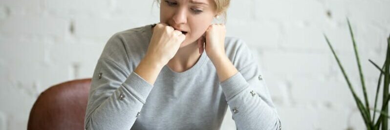 Portrait of a student girl sitting at the desk biting her fist
