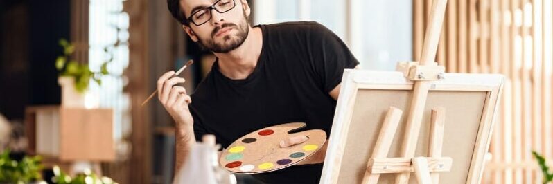 an painting with brush standing behind easel
