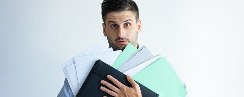 Puzzled office worker holding pile of documents