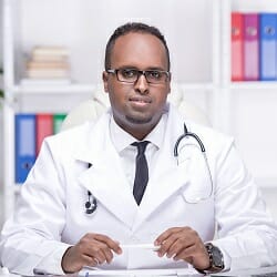 Young African American doctor is sitting in his office.