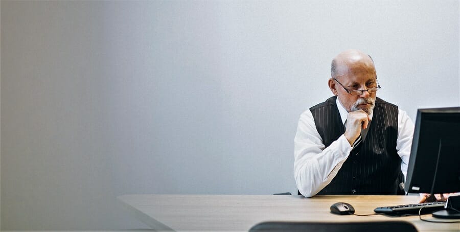 Senior manager at the office working on a computer