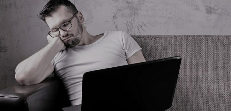 The guy in the white shirt sitting on the couch, fell asleep at work on a laptop. The concept of laziness, apathy, frustration, procrastination, the person at home. copy space.