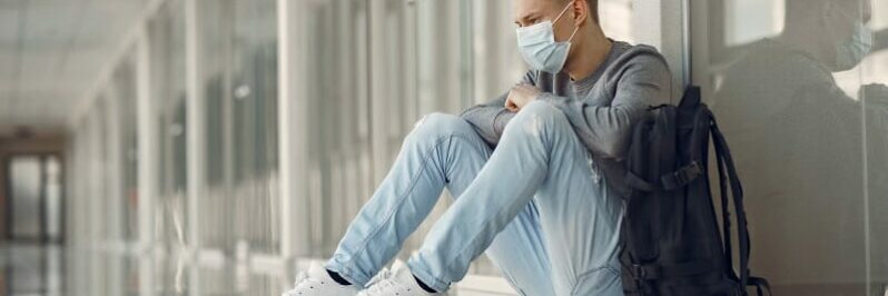 Man in a mask sitting in the hall of hospital
